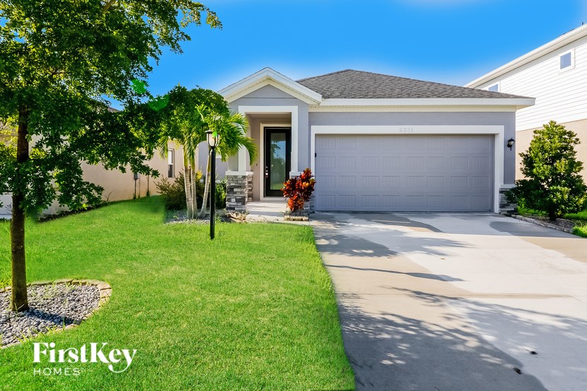 A house with a garage and a tree in front of it.