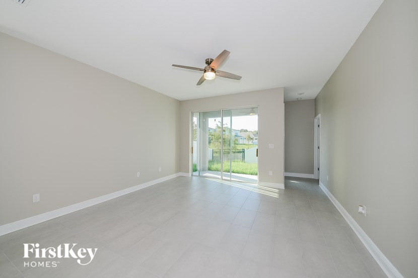 A spacious room with a ceiling fan and sliding glass doors leading to a balcony.