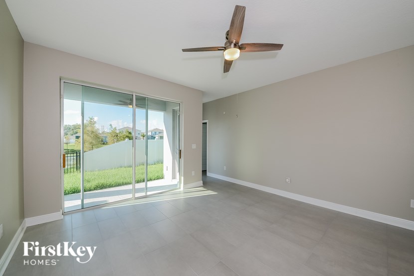 A spacious room with a ceiling fan and sliding glass doors leading to a backyard.
