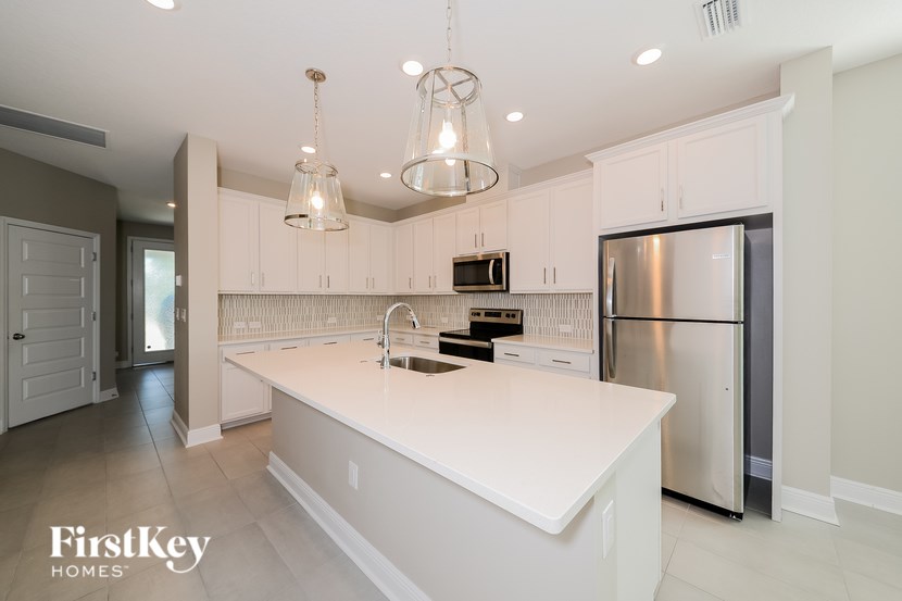 A modern kitchen with a stainless steel refrigerator and a white island.
