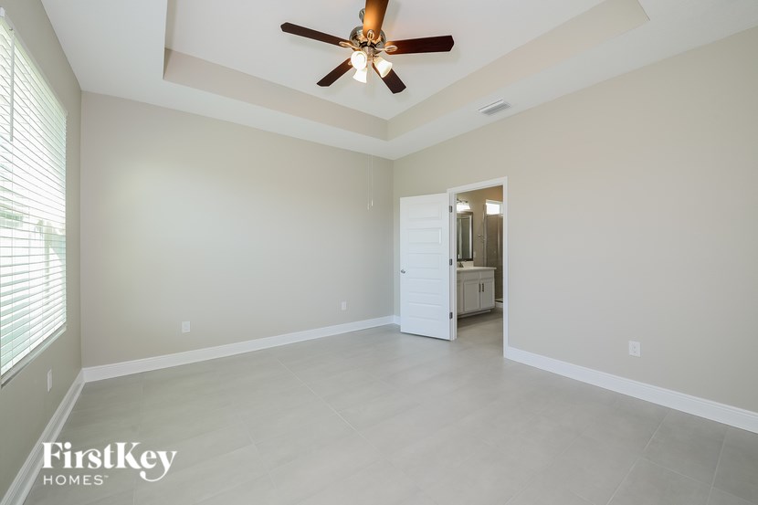 A spacious room with a ceiling fan and a door leading to another room.