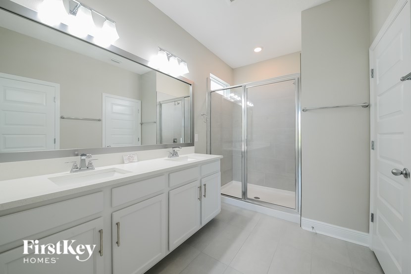 A bathroom with a sink, mirror, and shower.