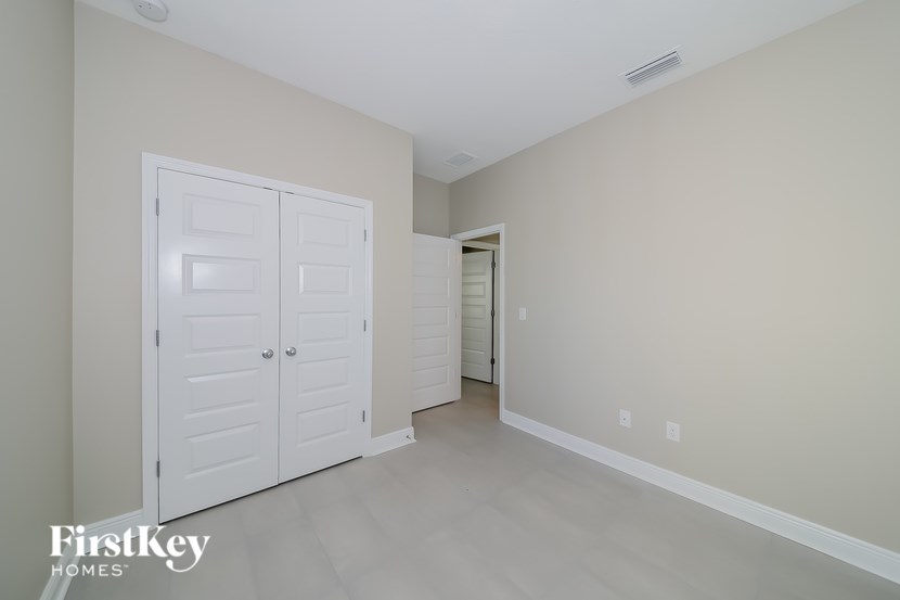A white closet with a door and a mirror on the wall.