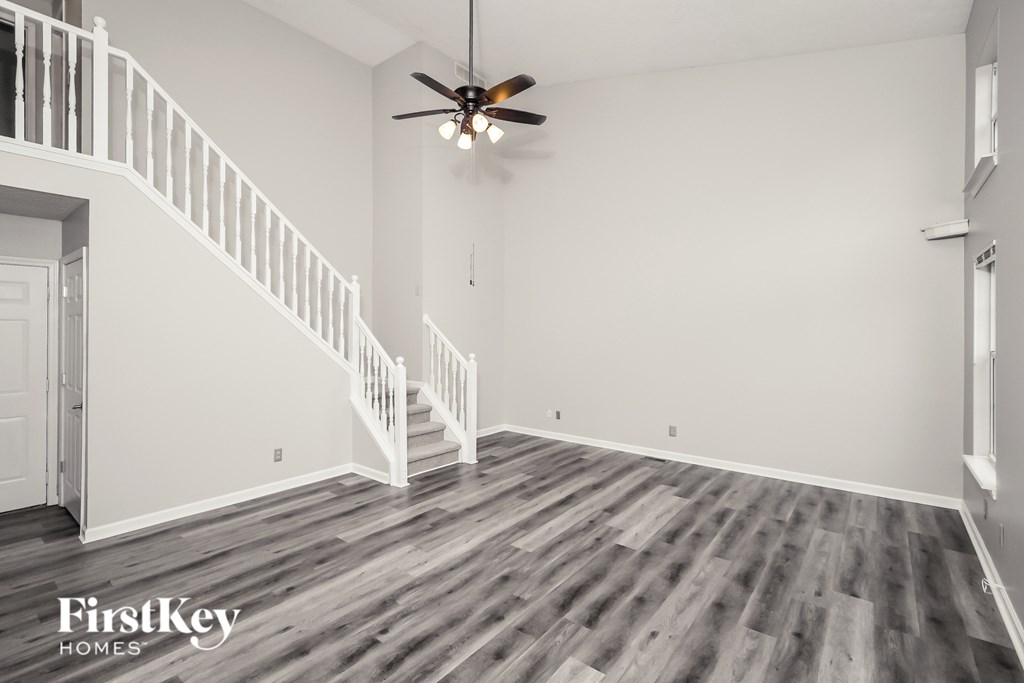 A spacious room with a staircase and a ceiling fan.