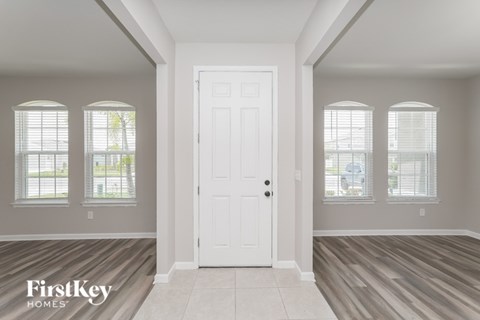 A room with a white door and windows with blinds.