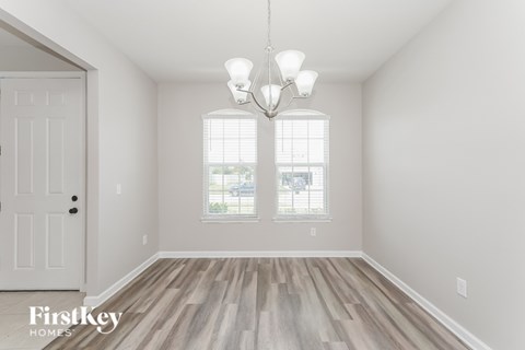 A room with a white door and a chandelier hanging from the ceiling.