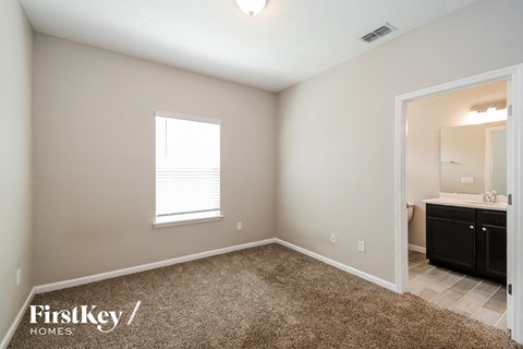 a bedroom with a carpeted floor and a bathroom with a sink