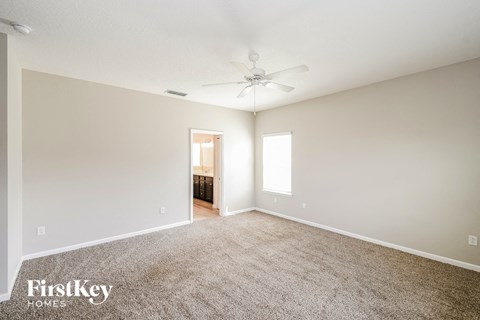 a spacious living room with carpet and a ceiling fan