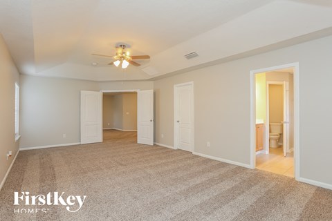 a spacious living room with carpet and a ceiling fan