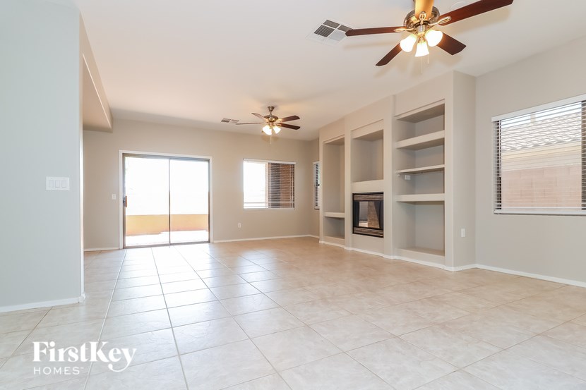 A spacious living room with a ceiling fan and tiled flooring.