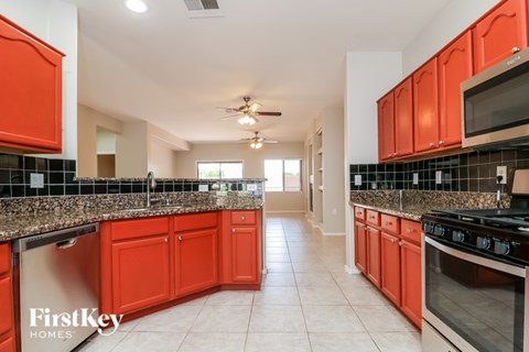 A kitchen with red cabinets and a black and white tiled backsplash.