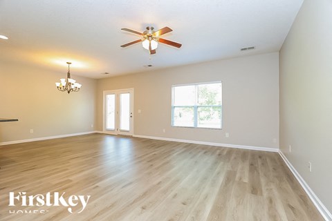 A spacious room with a ceiling fan and wooden flooring.