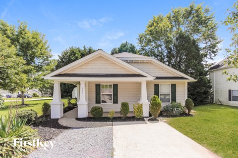 a small white house with white pillars and a driveway