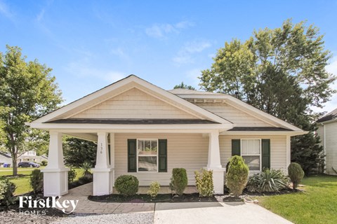 a small white house with white pillars and a porch