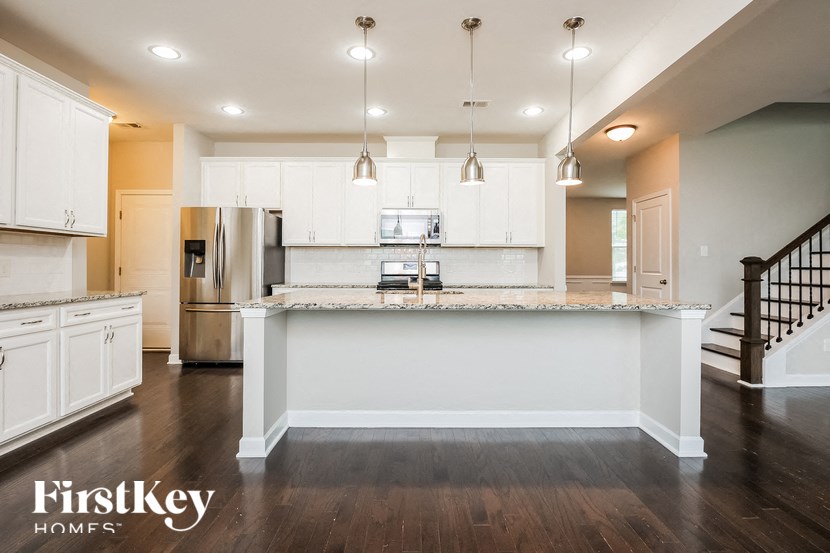 A kitchen with white cabinets and a marble island.