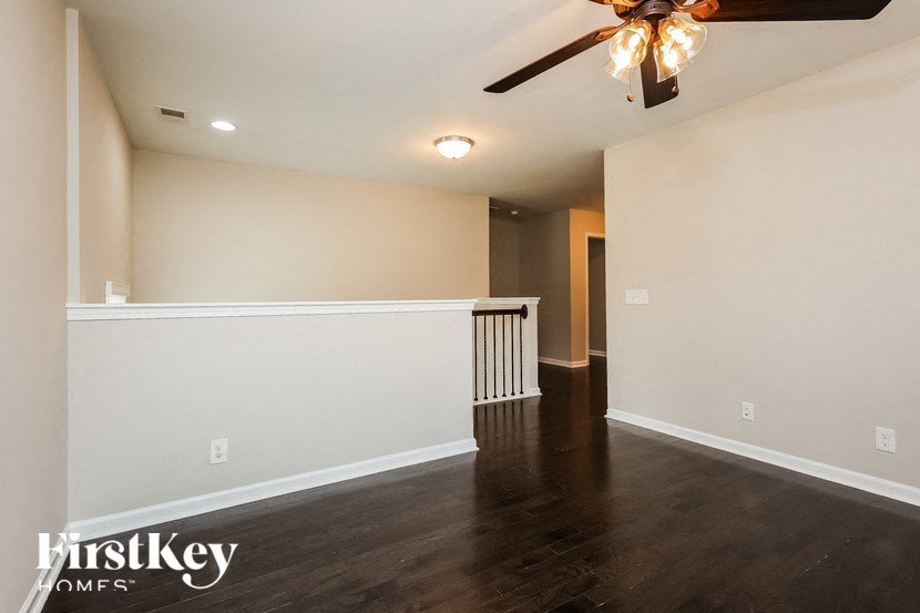 A room with a ceiling fan and wooden floors.