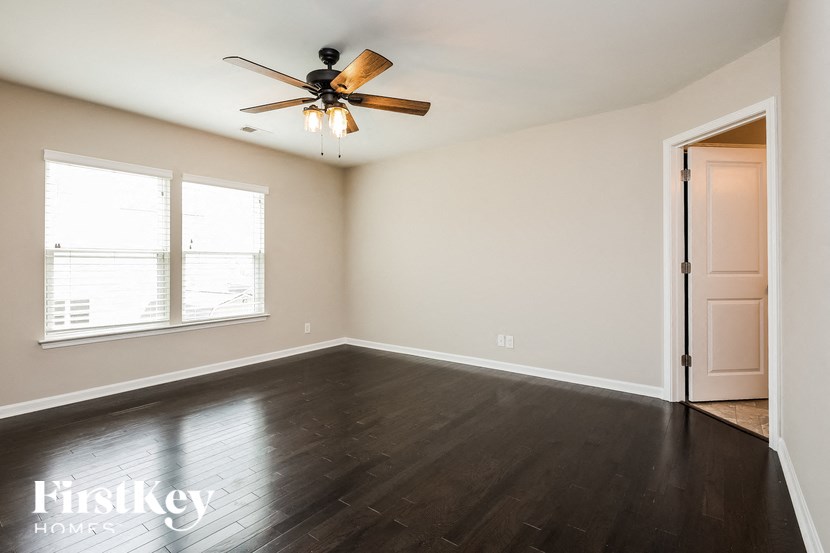 A room with a ceiling fan and wooden floors.