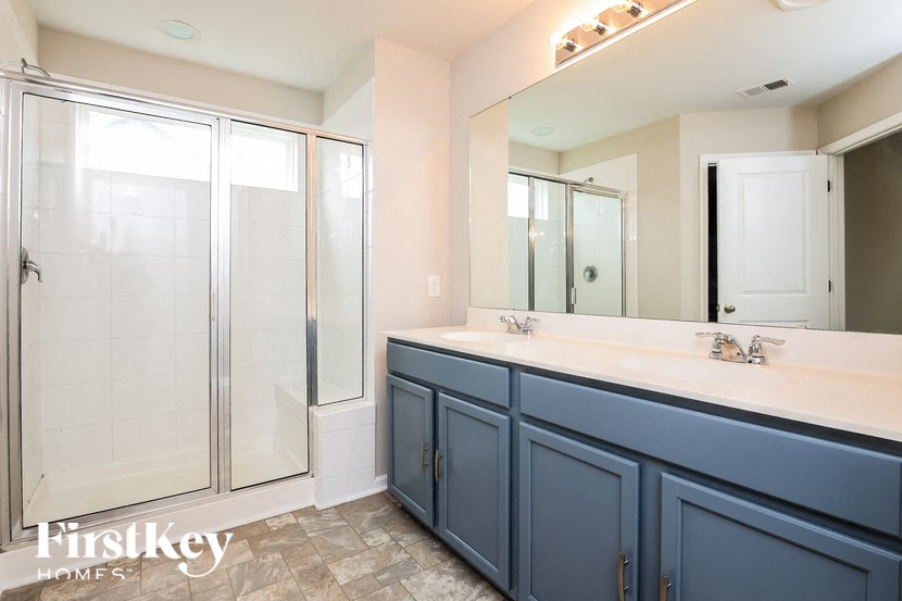 A bathroom with a blue cabinet and a glass shower door.