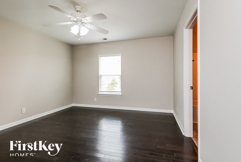 A room with a ceiling fan and wooden flooring.