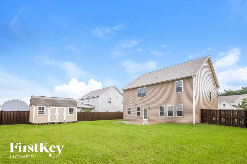 A house with a fence and a shed in the yard.