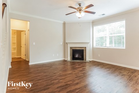 A spacious living room with a fireplace and a ceiling fan.