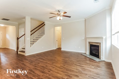 A spacious living room with wood flooring and a fireplace.
