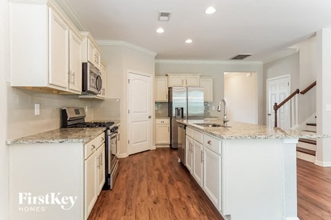 A kitchen with white cabinets and a FirstKey Homes logo.