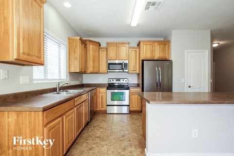 A kitchen with wooden cabinets and a stainless steel refrigerator.