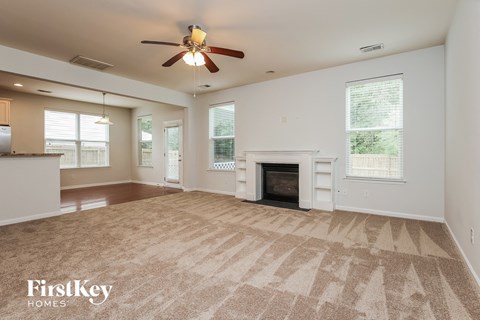 A spacious living room with a fireplace and a ceiling fan.