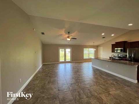 an empty living room and kitchen with a ceiling fan
