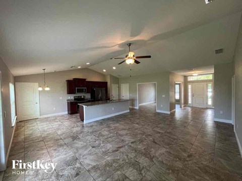 an empty living room and kitchen with a ceiling fan