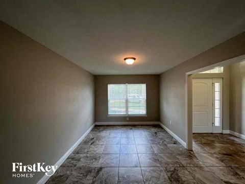 an empty living room with tile flooring and a window