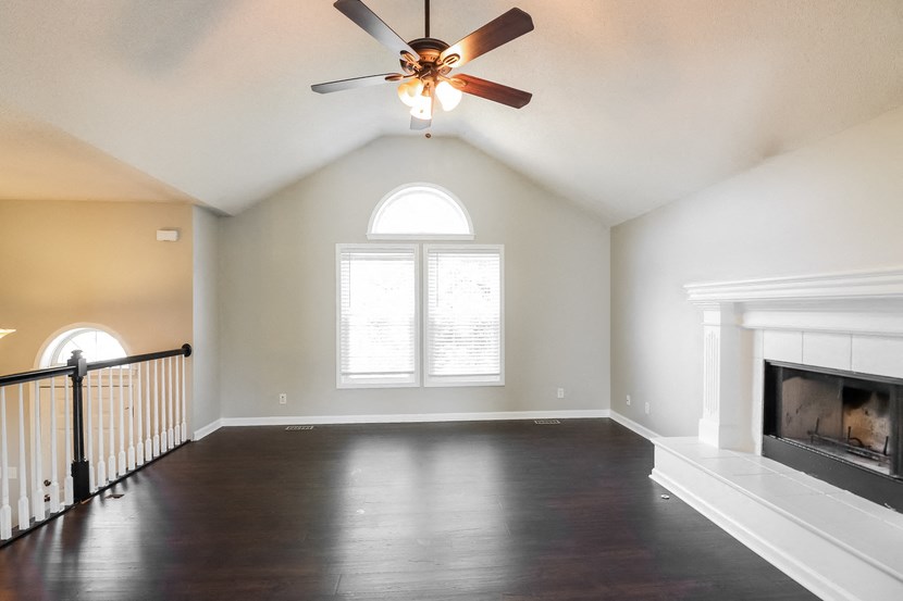an empty living room with a ceiling fan and a fireplace