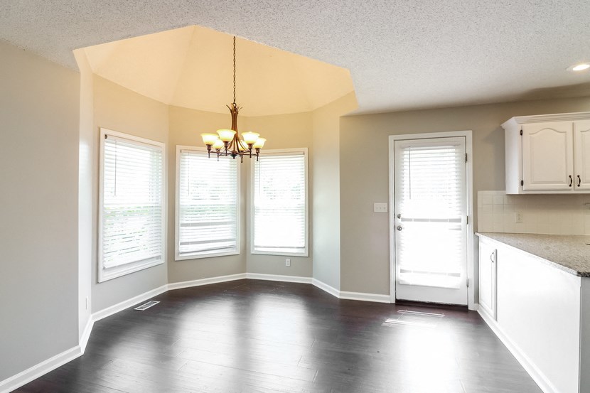 an empty kitchen with white cabinets and a chandelier