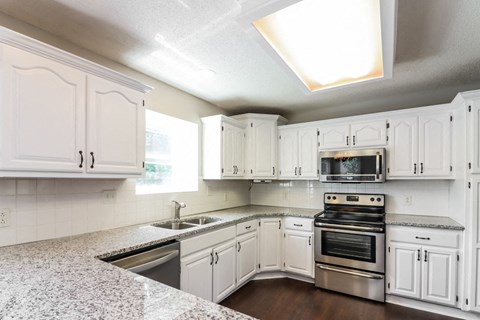 a kitchen with white cabinets and stainless steel appliances