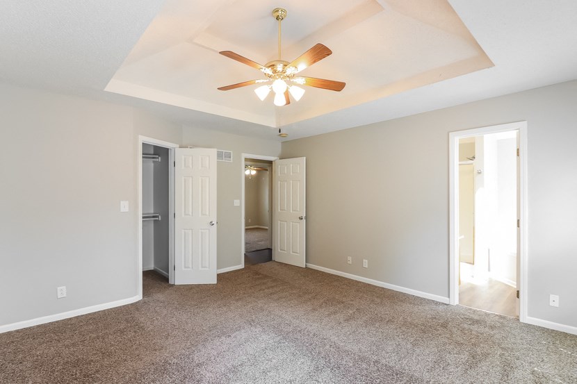 an empty living room with a ceiling fan