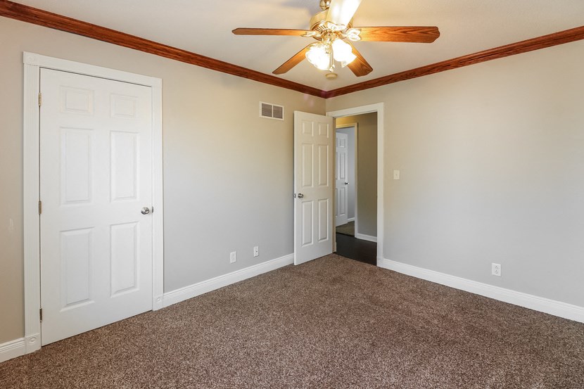 an empty living room with carpet and a ceiling fan