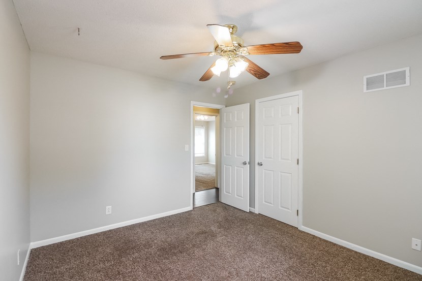a bedroom with a ceiling fan and a door to a closet