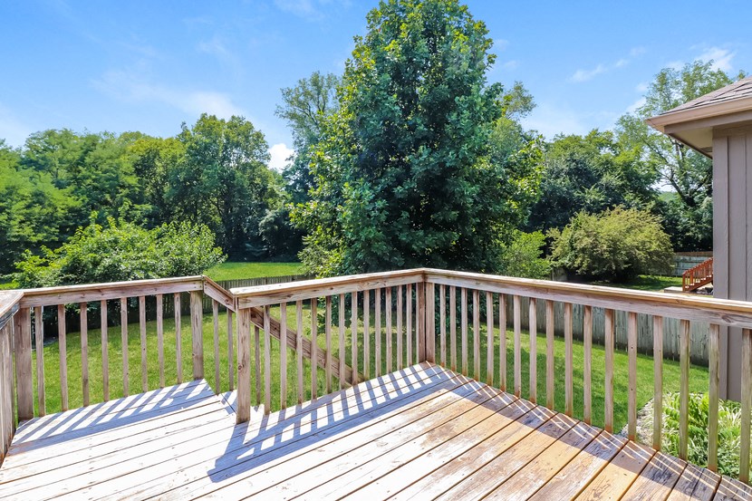 a deck with a view of a yard and trees