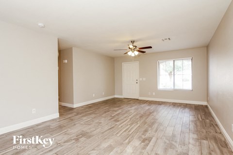 A spacious room with wooden flooring and a ceiling fan.