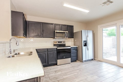 A kitchen with black cabinets and a white sink.