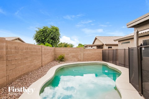 A small pool with a hot tub in the middle of a backyard.