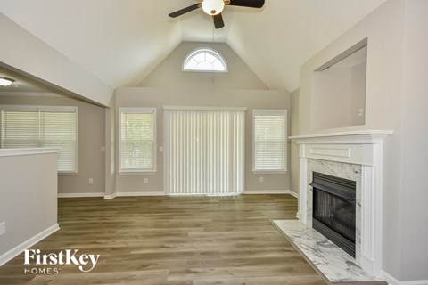 A spacious living room with a fireplace and a ceiling fan.
