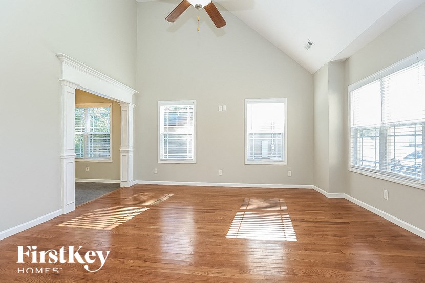 A spacious room with wooden flooring and a ceiling fan.