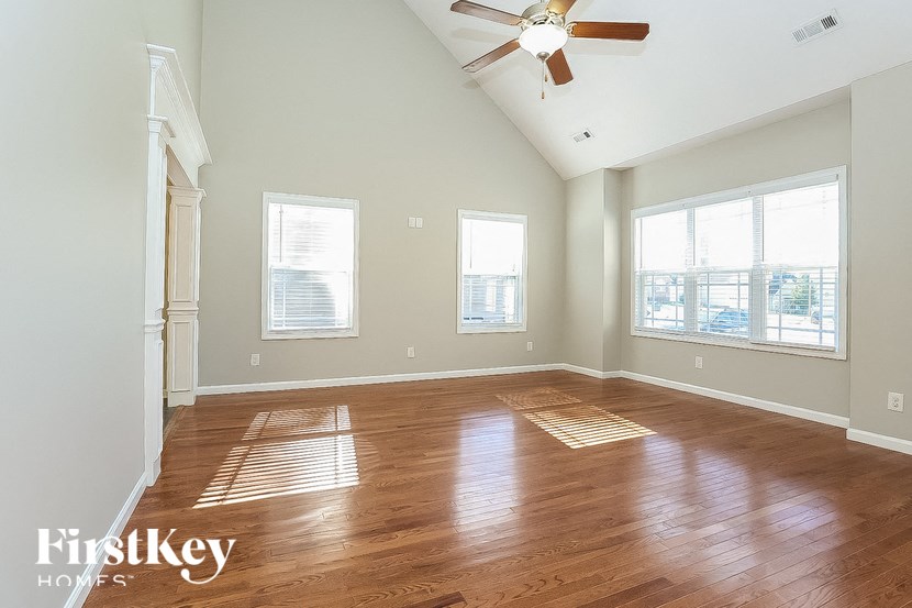 A spacious room with wooden floors and a ceiling fan.