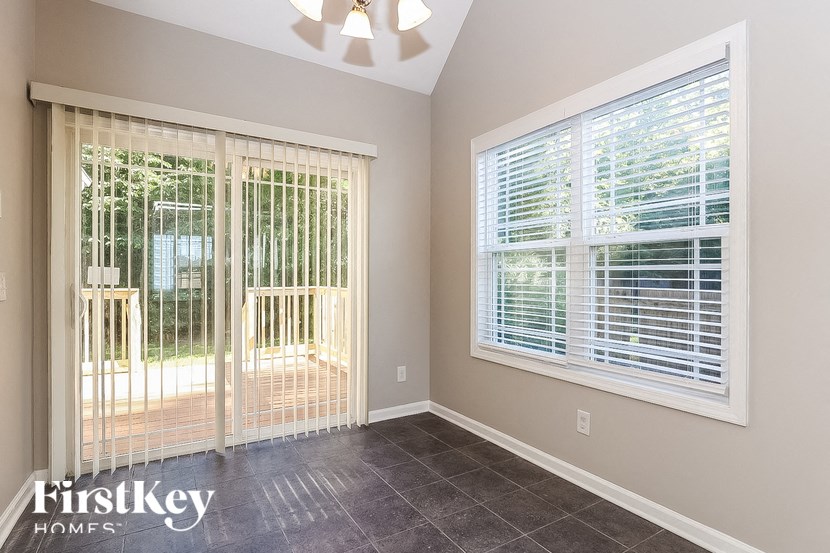 A room with a sliding glass door and a window with blinds.