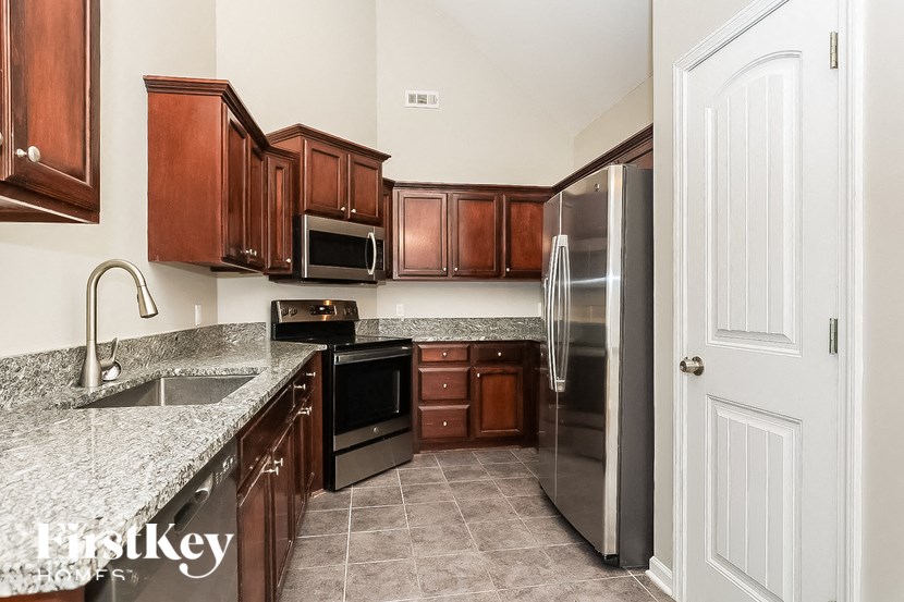 A kitchen with brown cabinets and a stainless steel refrigerator.