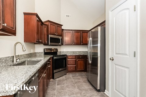 A kitchen with brown cabinets and a stainless steel refrigerator.