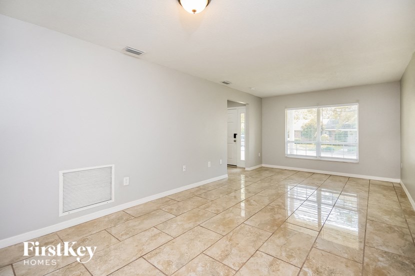 a spacious living room with tile flooring and a window