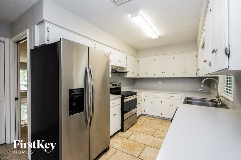 a kitchen with white cabinets and a stainless steel refrigerator